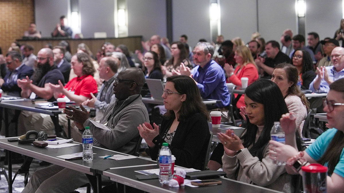 Conference attendees applaud during a keynote presentation at the 2024 Developing Data Analytics Capabilities Conference.