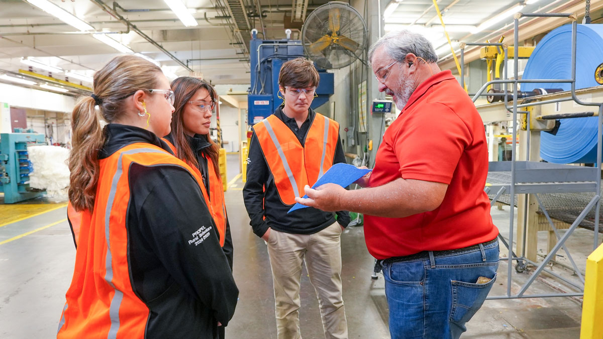 PROPEL Rural Scholars Macy Hall, Lauren Park and Chase Walker listen to Hollingsworth & Vose Production Manager Tony Gibson, right, as he shows them filter paper produced at the Hawkinsville plant.