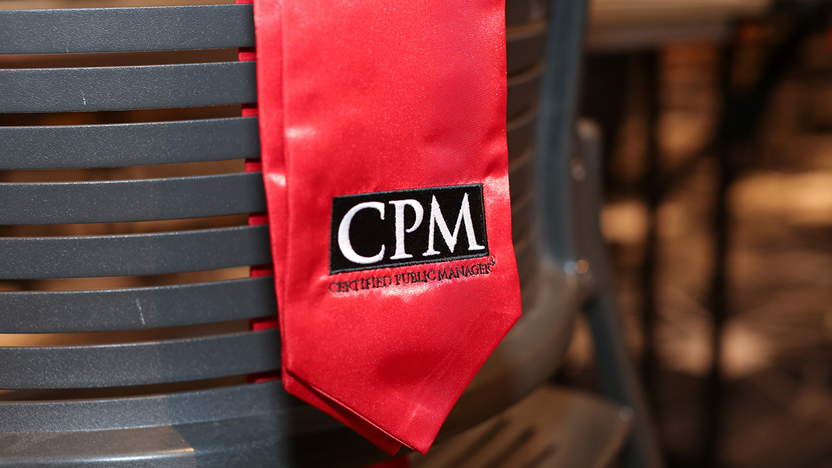 CPM graduation stole draped over the back of a chair